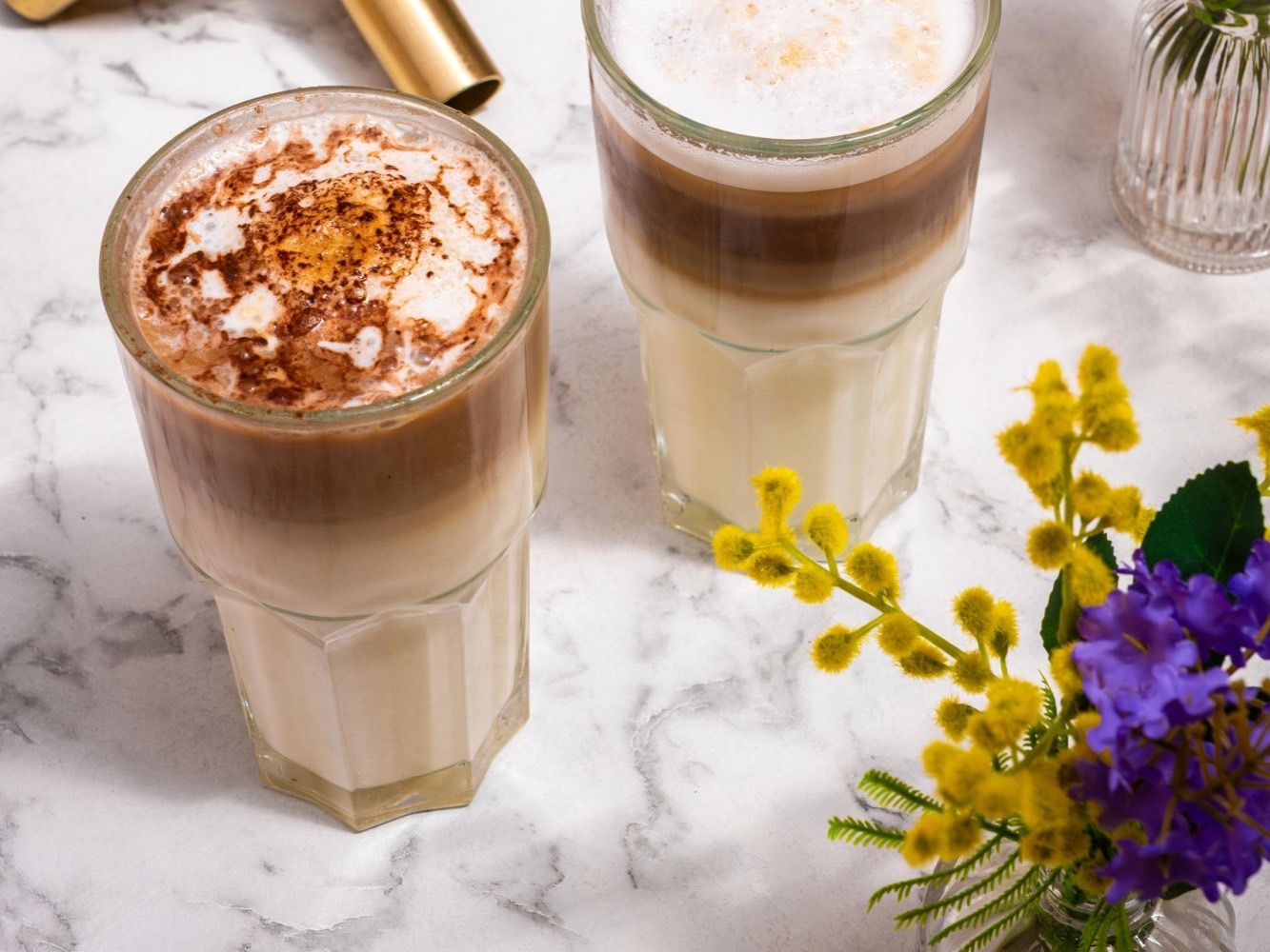 Deux lattes préparés au comptoir de PEACH, cacao saupoudré, soliflores fleuris sur le marbre