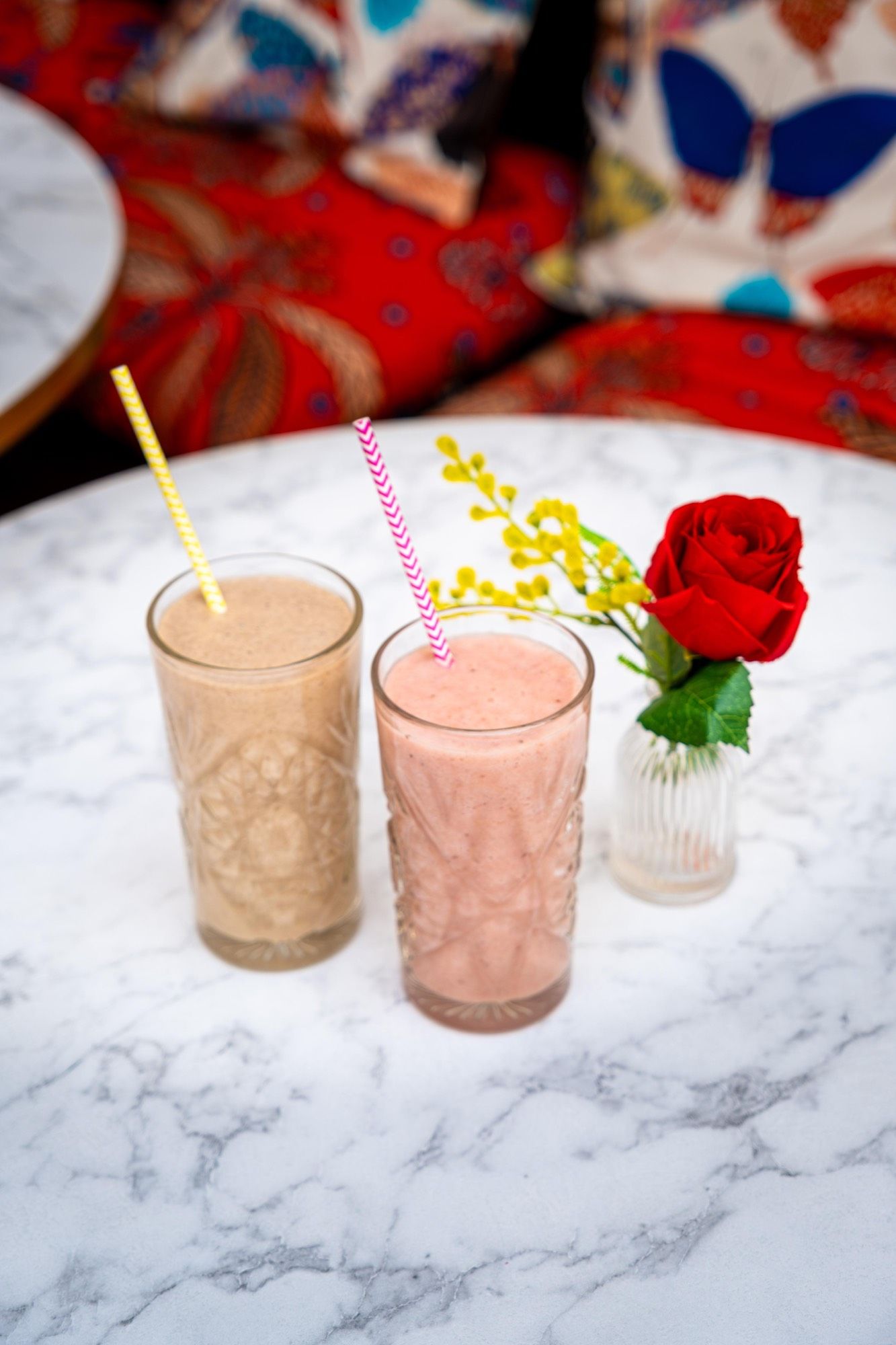 Deux smoothies maison — Banana et Pineberry — avec pailles en papier et rose rouge en soliflore